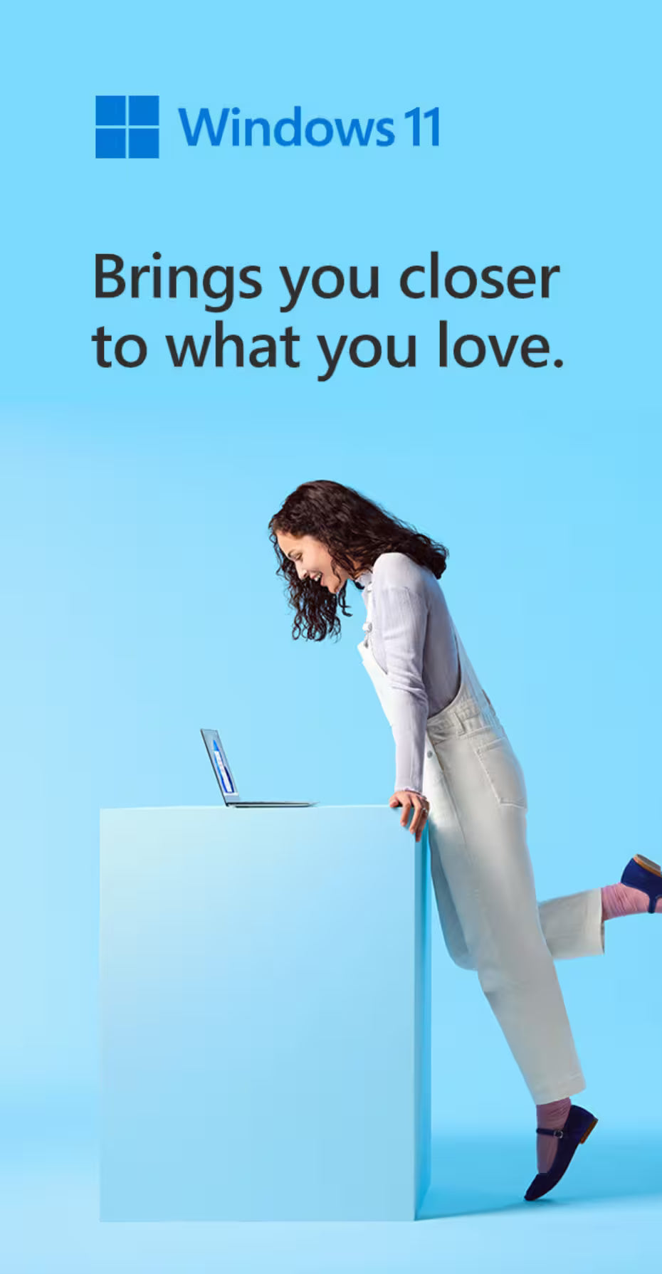 Windows 11 promotional graphic with the Windows logo and text 'Brings you closer to what you love.' on a light blue background, plus a woman leaning over a pedestal with a laptop.