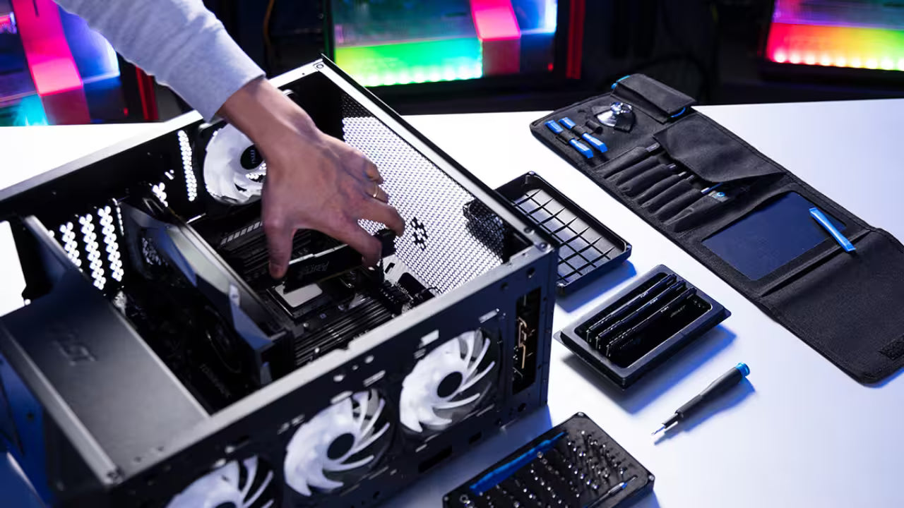 Hands-on PC assembly showing the installation of memory modules into a high-end gaming desktop with a specialized tool kit on a white desk